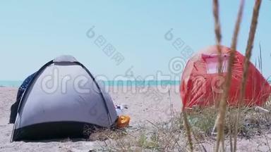 旅游帐篷矗立在沙滩上。 站在荒无人烟的沙滩上的旅游帐篷。